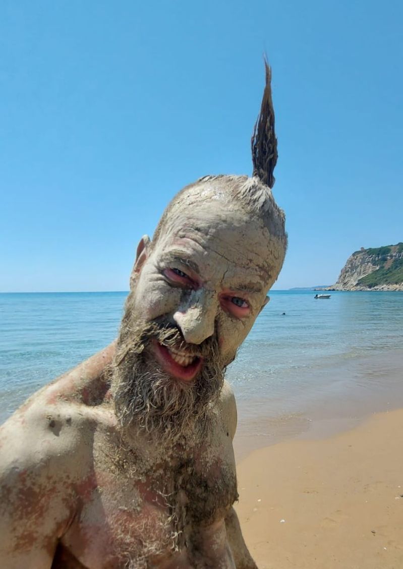Florian Köhler mit Heilerde am Strand von Korfu – spontaner Moment beim Männer-Retreat.
