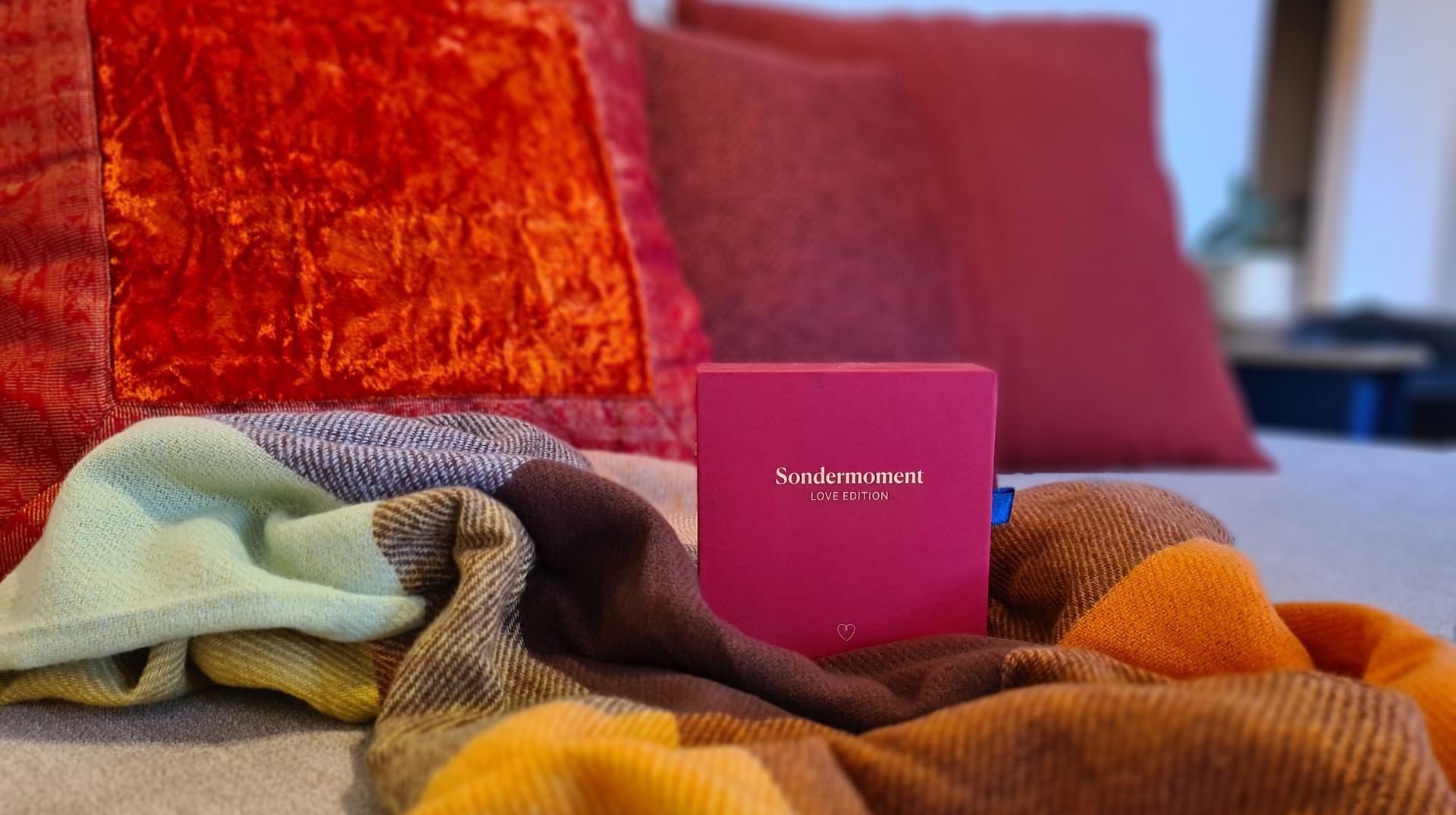Eine Kuscheldecke liegt auf einem Sofa - mit einem Spiel für 2 - Symbol für Zweisamkeit