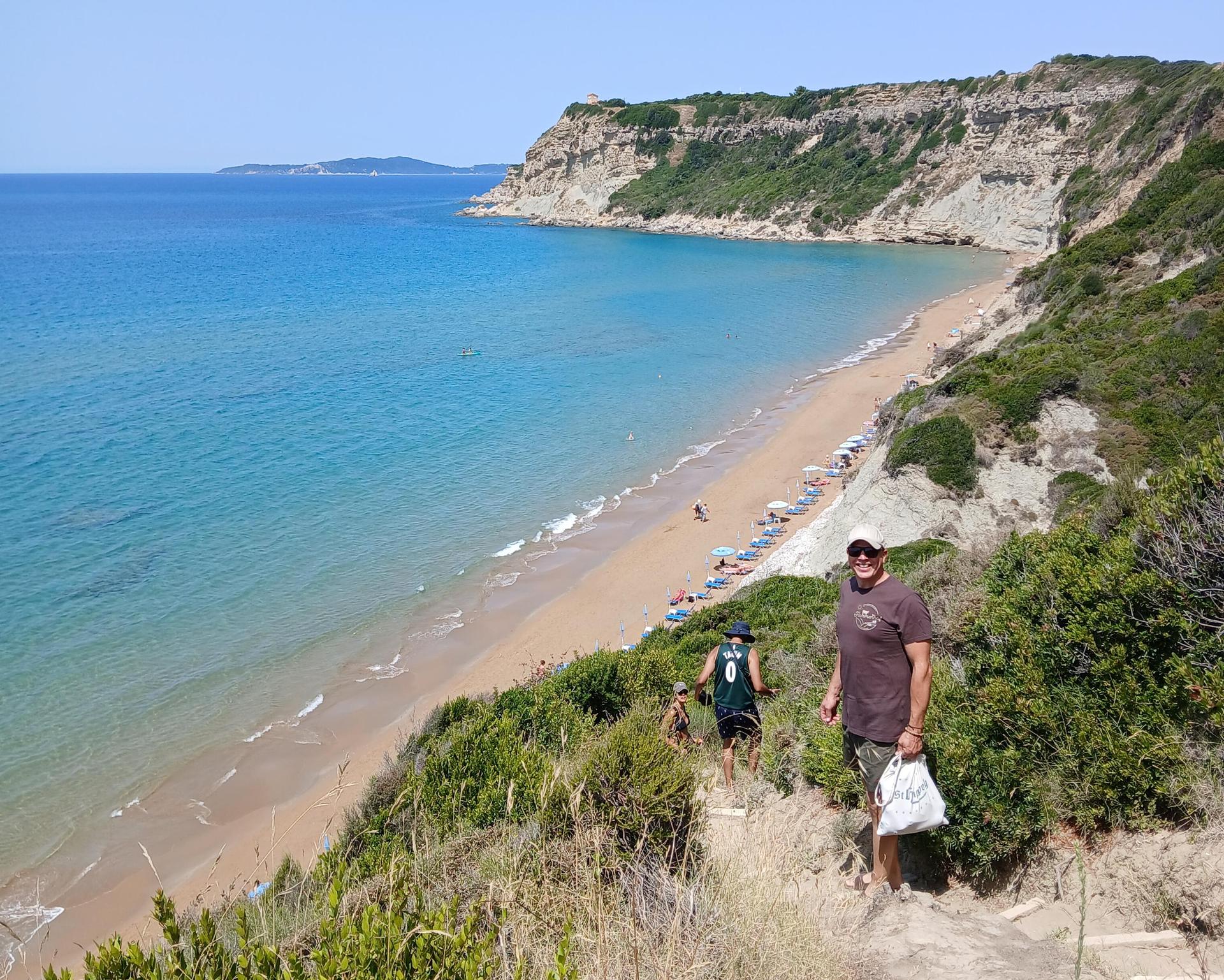 Ein Mann auf dem Weg zum Strand lächelt glücklich in die Kamera auf Korfu beim Retreat
