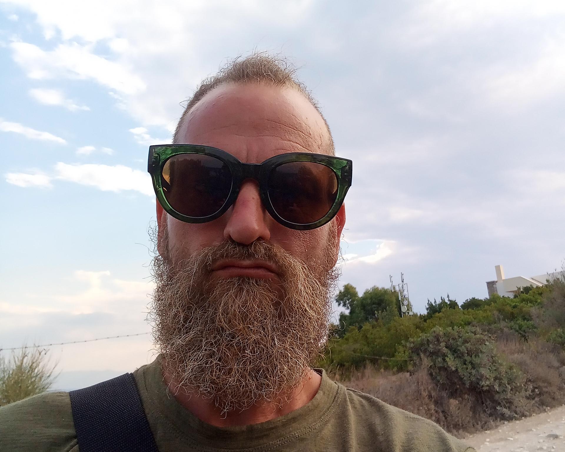 Ein Mann auf Korfu mit einer großen Sonnenbrille zieht eine Grimasse